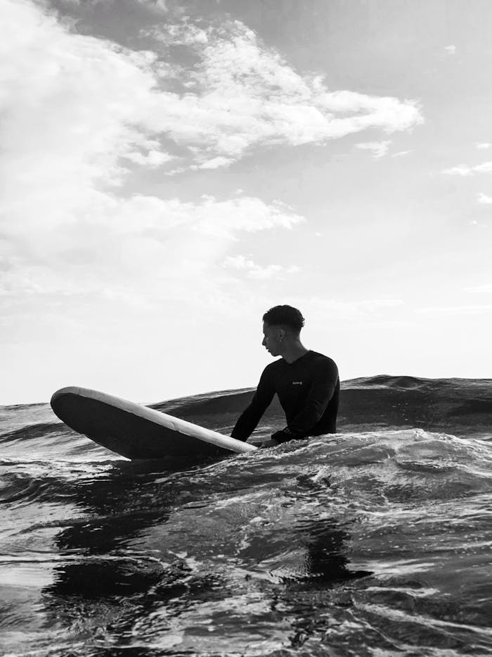 A surfer on a board navigating ocean waves in black and white.